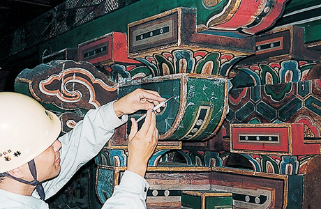 剥落止め工事作業風景　和紙の上から絵具層の裏に剥落止め液を注入する